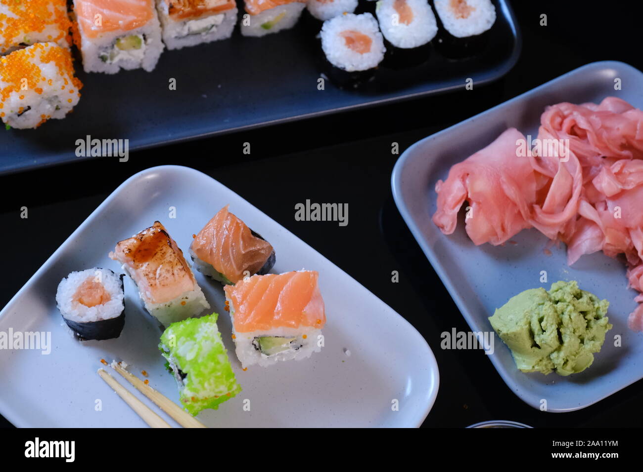 Rotolo di Sushi con pesce e frutti di mare, il wasabi e lo zenzero. Rotolo di Sushi con salmone su una tavola nera. Foto Stock