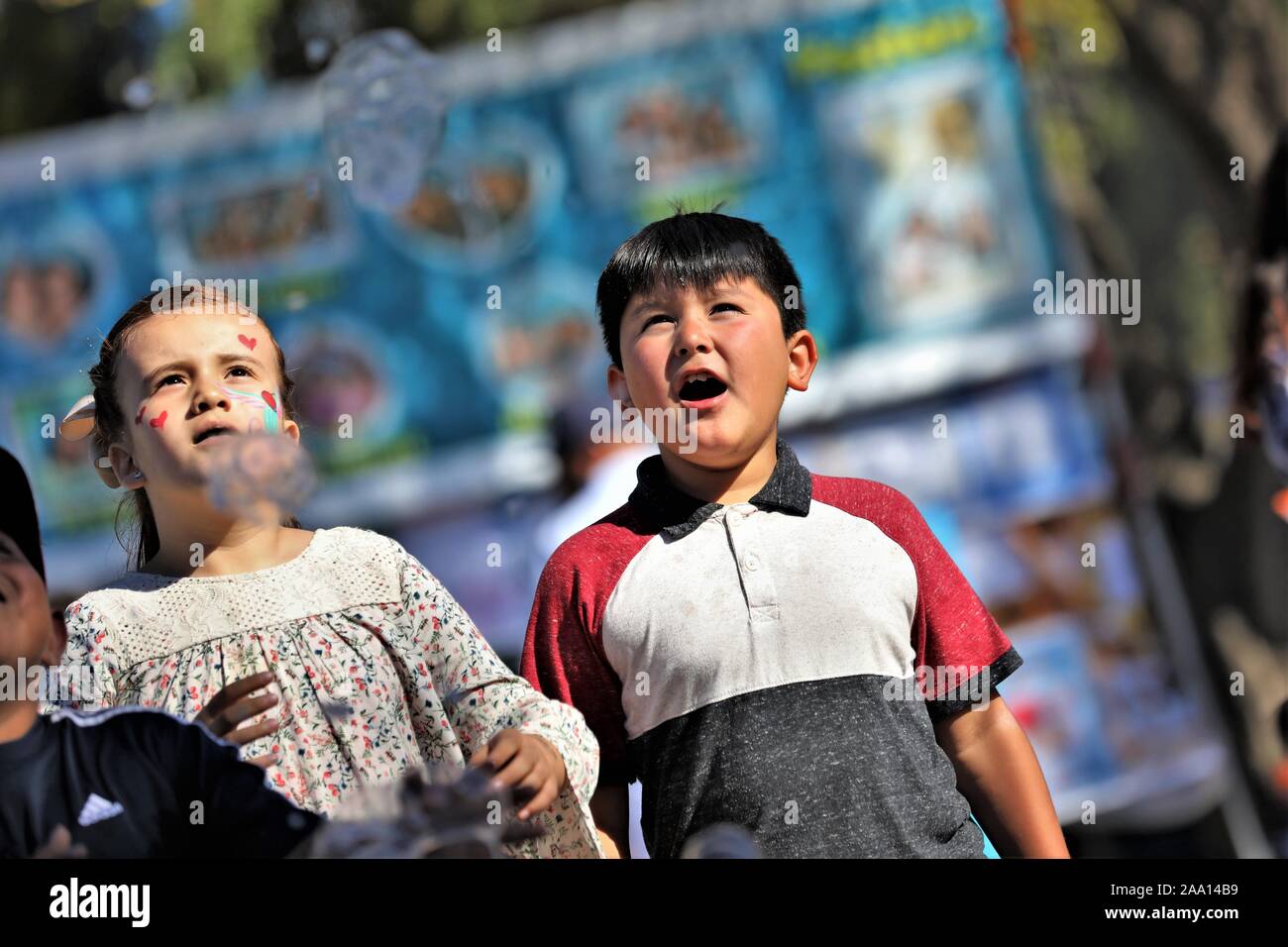 Ispanico messicano latina i bambini, i ragazzi e le ragazze a caccia di bolle dal circo fair act fatta con acqua e sapone per pubblico spettacolo e divertimento per tutta la famiglia Foto Stock