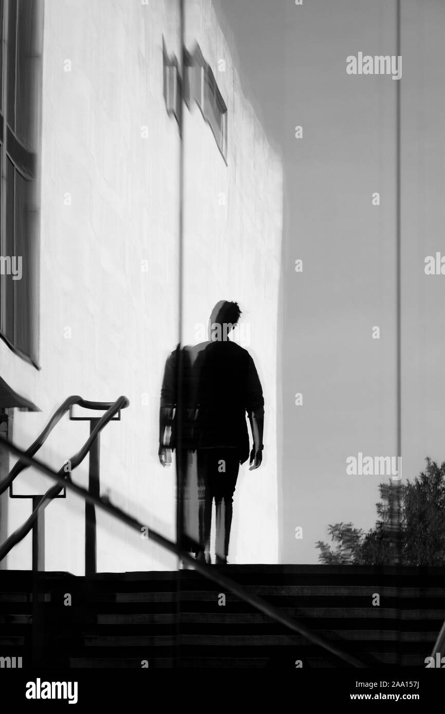 Fotografia di strada bianca e nera a Londra: Riflesso di figura maschile silhouette, Londra, Regno Unito Foto Stock