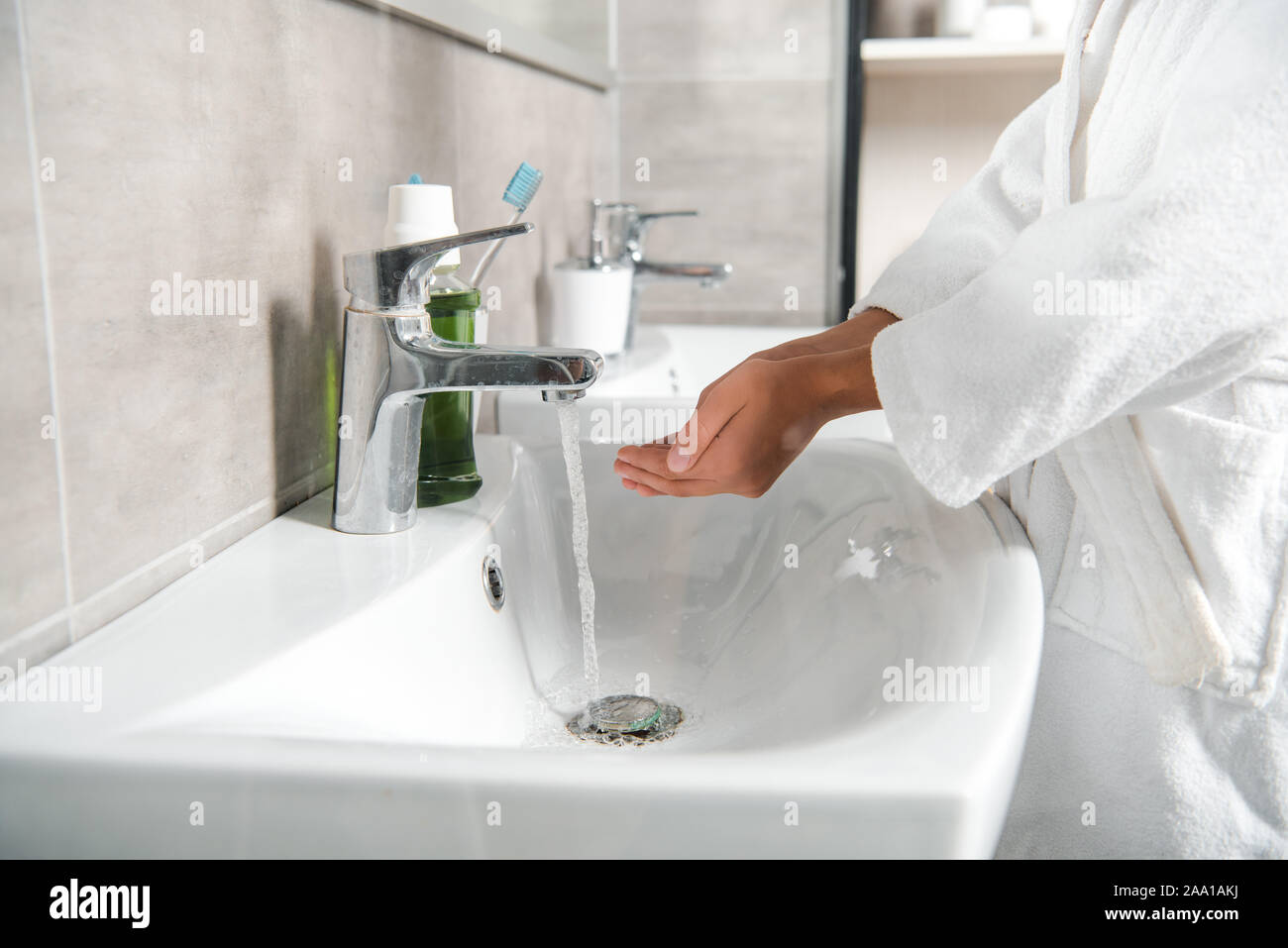 Vista ritagliata dell uomo in bianco vasca a tazza con le mani vicino al rubinetto con acqua Foto Stock