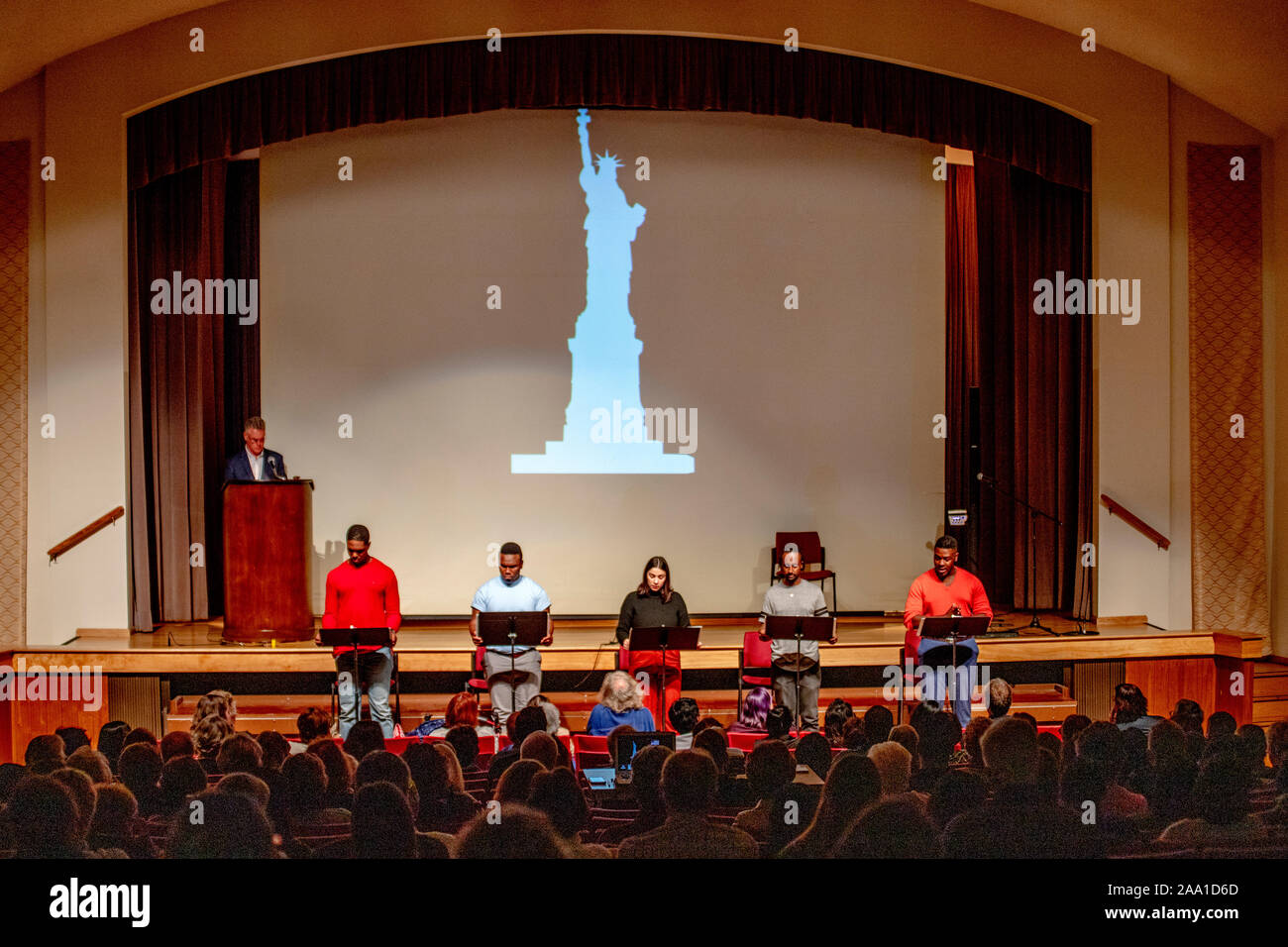 Una silhouette della Statua della Libertà è mostrato in corrispondenza di una multirazziale teatro lettori a discutere dei diritti civili in arancione, CA. Foto Stock