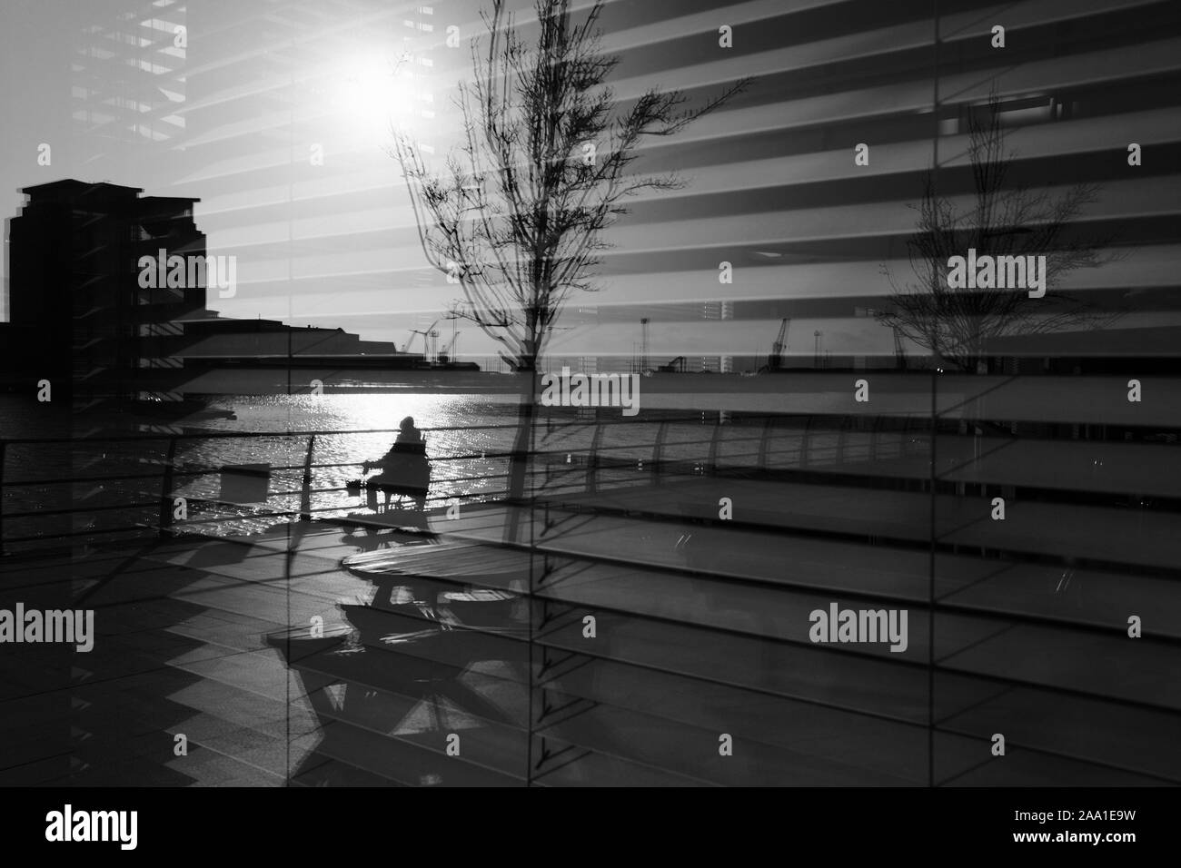 Mobilità scooter che viaggia lungo la banchina a Swansea il quartiere marittimo con la scena e occupante in silhouette in inverno il sole mattutino Foto Stock