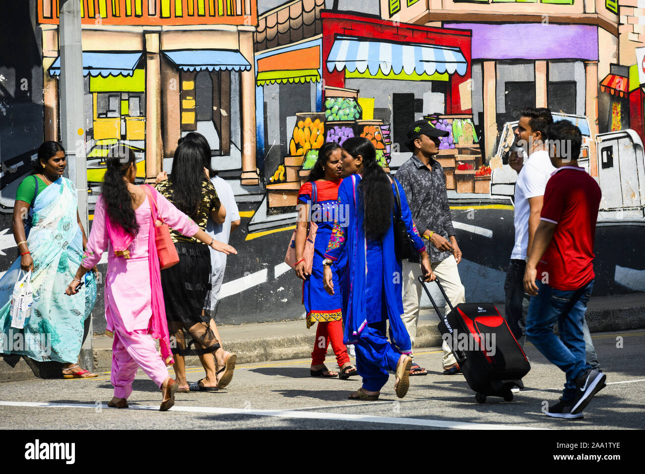 Alcune persone sono in piedi davanti un bel dipinto graffiti su una parete in Little India. Foto Stock