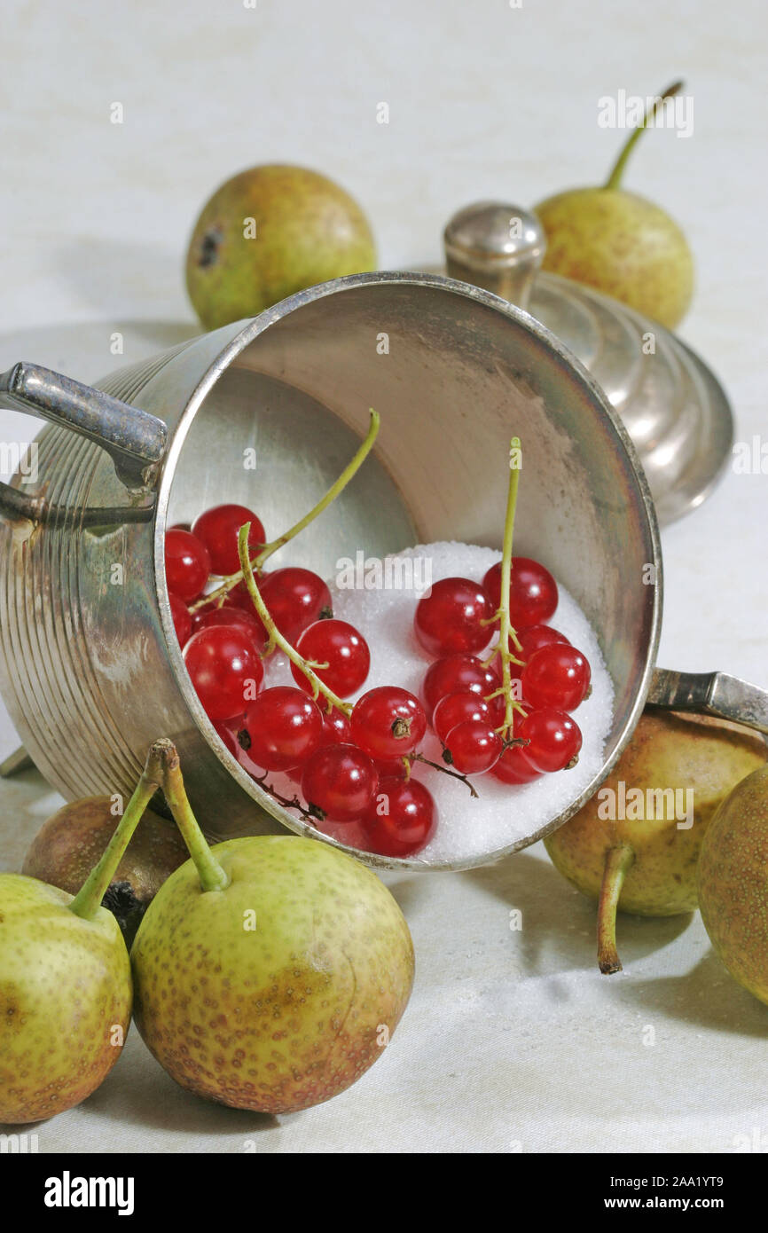 Zuccurbirnen liegen neben einem mit Zucker gefüllten silbernen Becher. Im Becher liegen Rote Johannisbeeren / Pere (Zuccurbirnen) sono lieing vicino a s Foto Stock