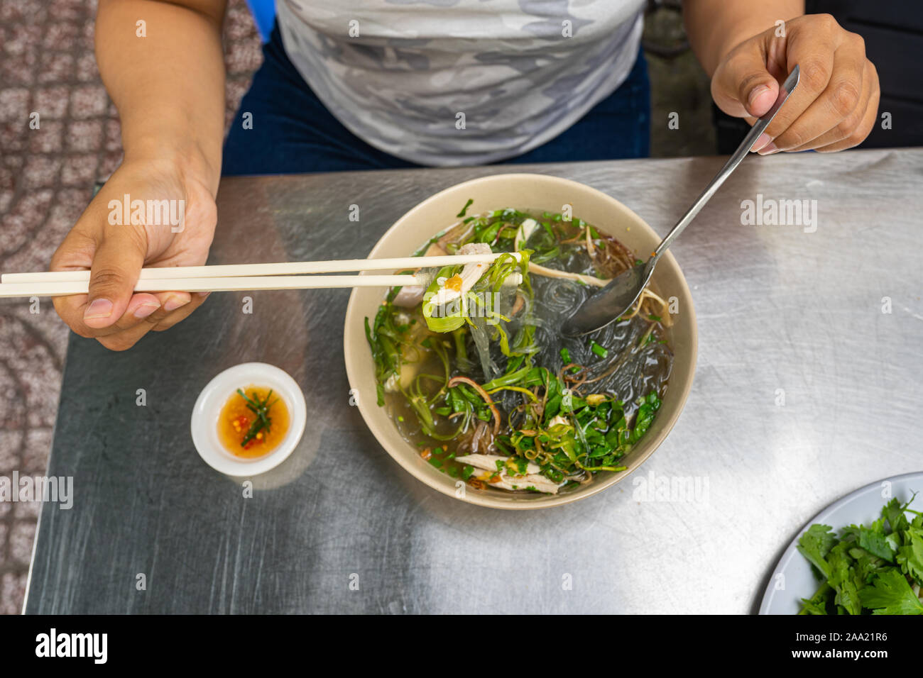 Donna di mangiare pollo vietnamita zuppa Pho a street food vendor Foto Stock