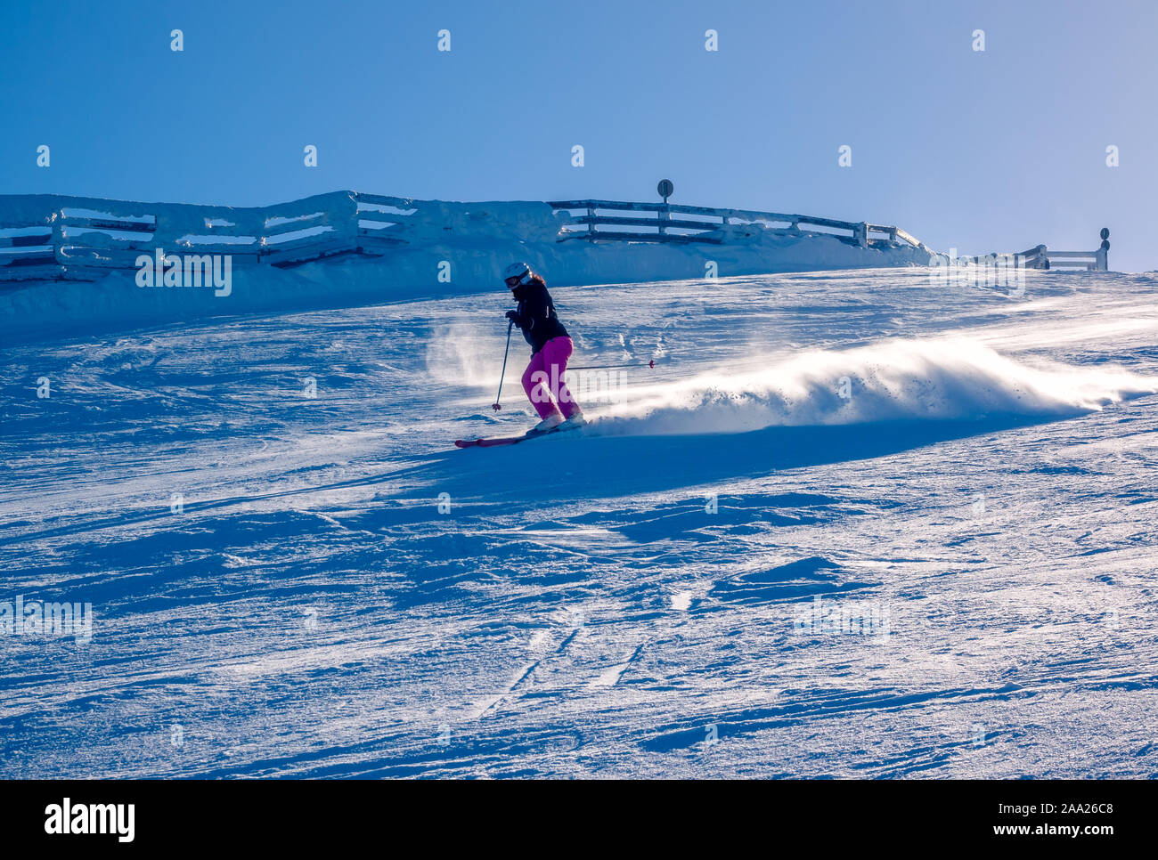 Giornata di sole su una neve sulle piste da sci. Irriconoscibile ragazza sciatore solleva polvere di neve Foto Stock