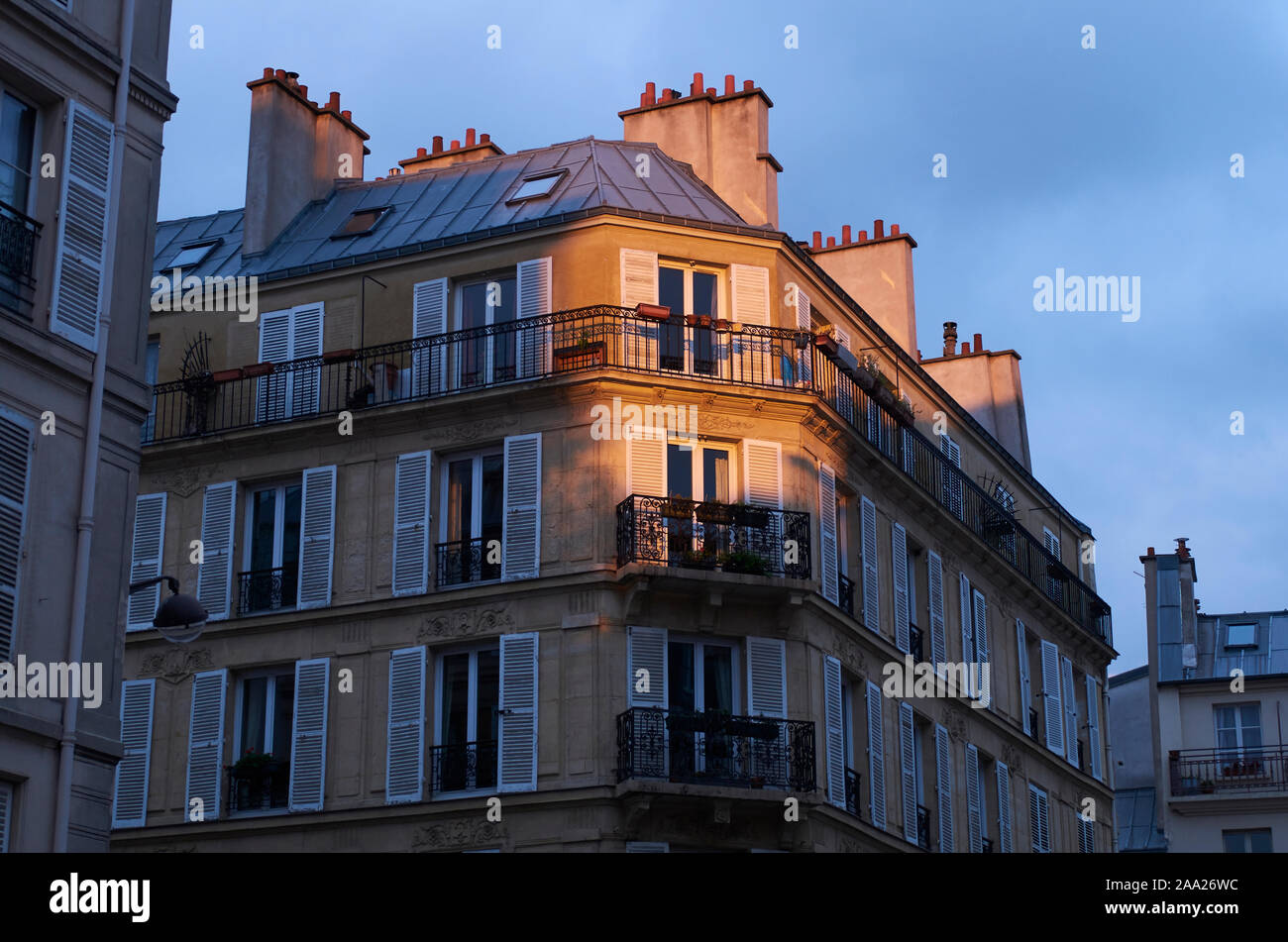 Delicato giallo arancio sole serale colpisce i piani superiori di un tipicamente Parisien edificio residenziale durante il tramonto. Foto Stock