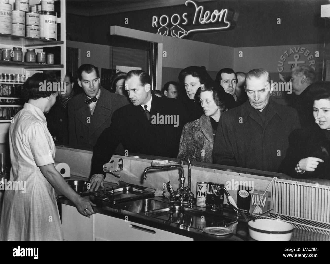 La cucina degli anni cinquanta. Una mostra a un pubblico fiera consumatori sta succedendo e visitatori presso il display di una cucina moderna sono interessati a saperne di più. Una donna in stand risponde alle domande. La mostra è chiamato a casa e famiglia e l'acciaio inox lavello da cucina è grande novità quest anno 1950. Svezia Foto Stock