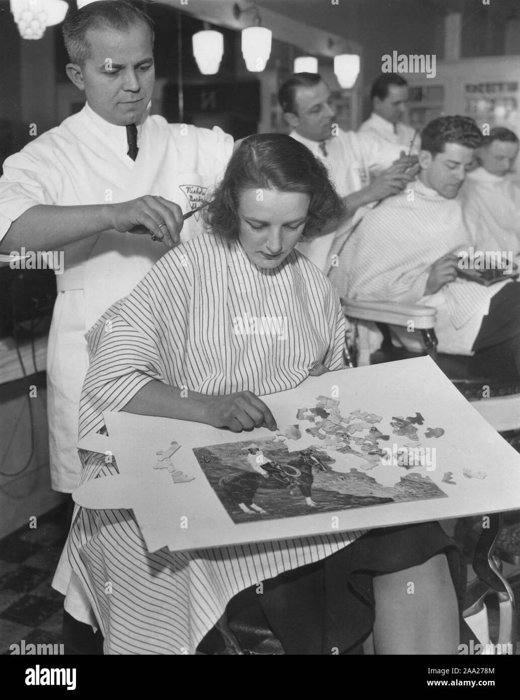 Donna al parrucchiere nel 1940s. Pur essendo di ottenere un taglio di  capelli e un nuovo taglio di capelli lei layes un puzzle. Il puzzle è di un  cowboy a cavallo. 1940s