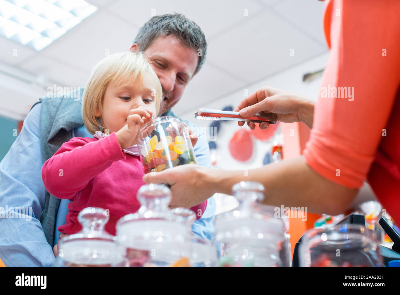 Saleslady per dolci di consegnare alcuni dolci per un bambino Foto Stock