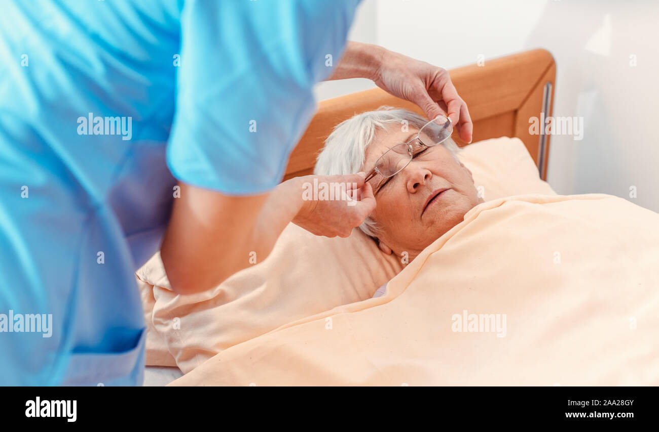 L'infermiera avendo cura di sleeping senior donna nella casa di cura Foto Stock