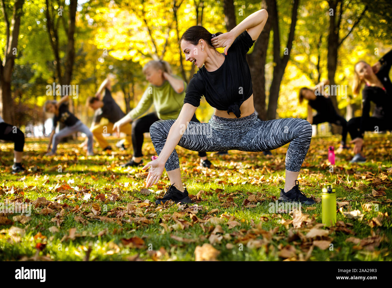 Un folto gruppo di persone facendo allenamento all'aperto sul verde del prato in posizione di parcheggio Foto Stock
