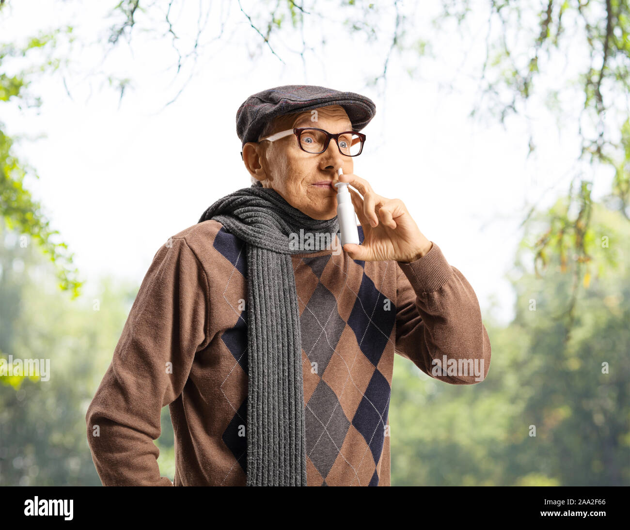 Senior uomo mediante spray nasale all'aperto sotto gli alberi Foto Stock