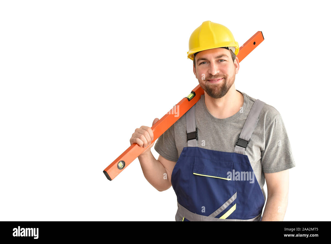 Allegro lavoratore edile - artigiano in abiti da lavoro con un livello di spirito su sfondo bianco Foto Stock