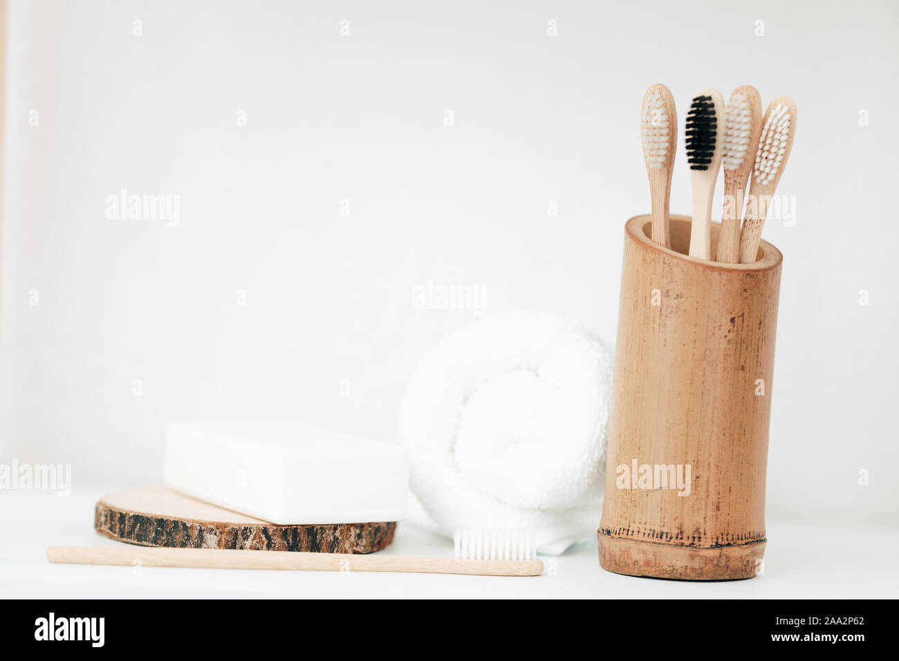 Gli spazzolini da denti di bambù in un contenitore accanto a una barra di sapone e un asciugamano Foto Stock