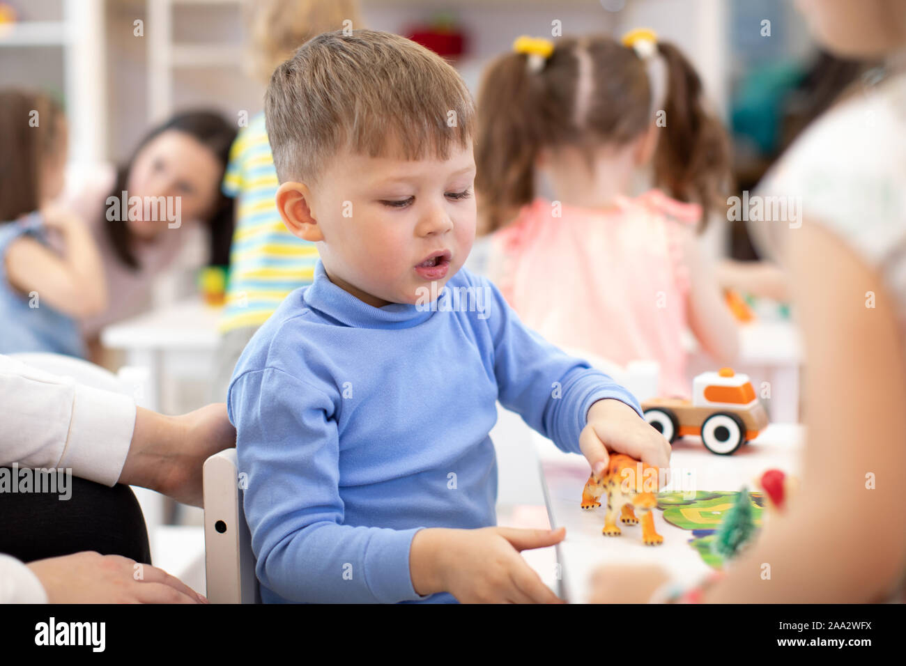 Preschooler gioca giocattolo animali in asilo nido. Gruppo di bambini in età prescolare sulla lezione in classe Foto Stock