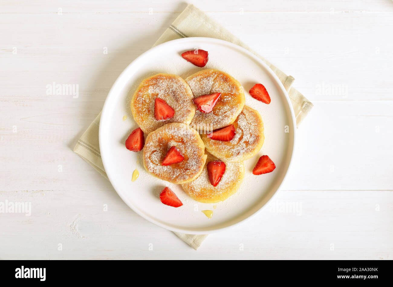 Cottage cheese pancake con fette di fragola e miele. Una sana prima colazione. Vista superiore, laici piatta Foto Stock