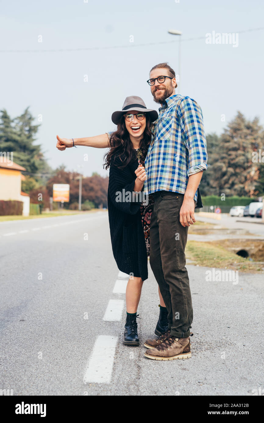 Felice Bella coppia Giovane outdoor autostop divertendosi throughfare - viaggio, concetto di trasporto Foto Stock