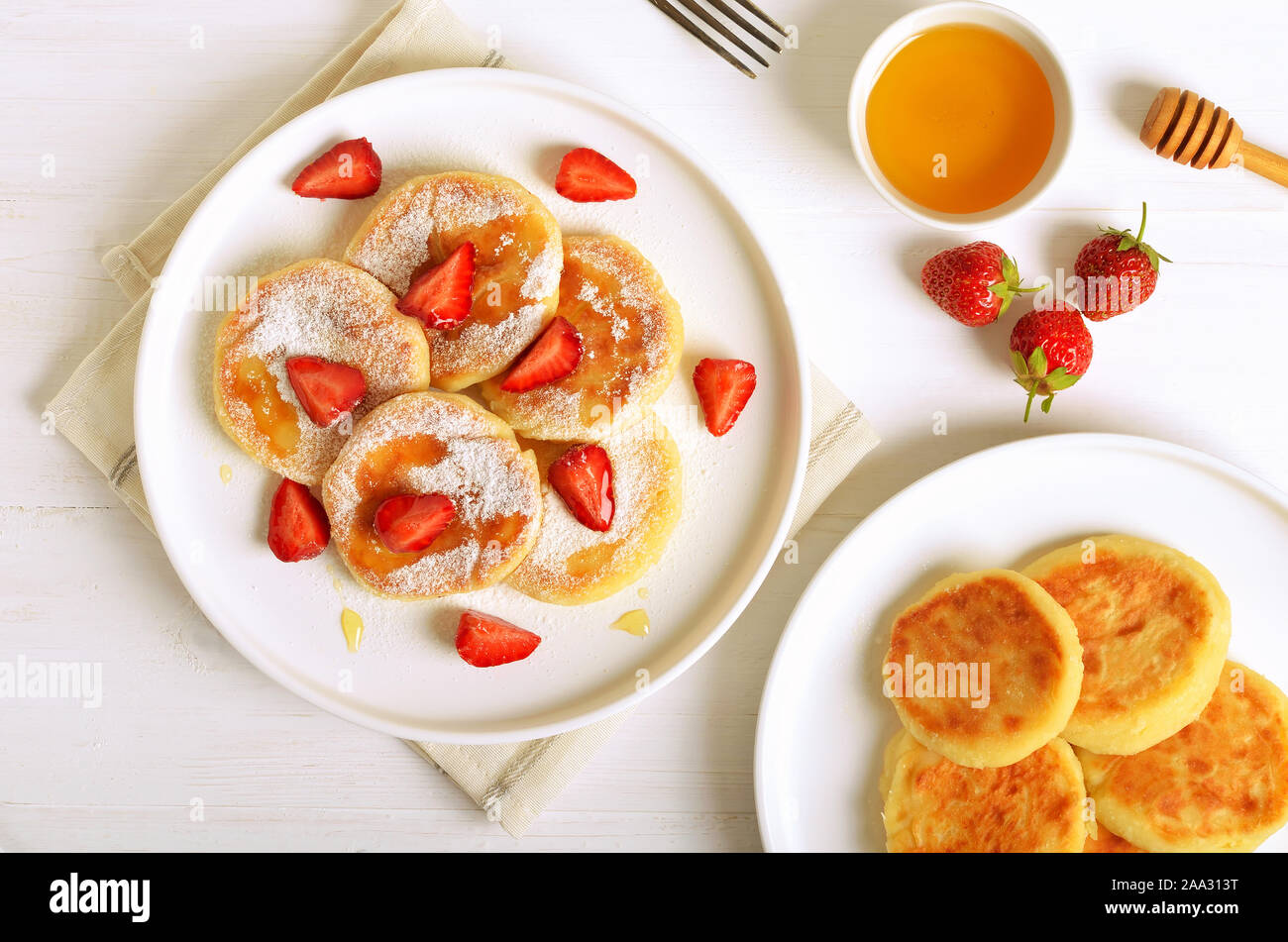Cottage cheese pancake con fette di fragola e miele. Una sana prima colazione. Vista superiore, laici piatta Foto Stock
