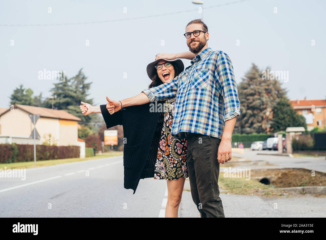 Felice Bella coppia Giovane outdoor autostop divertendosi throughfare - viaggio, concetto di trasporto Foto Stock