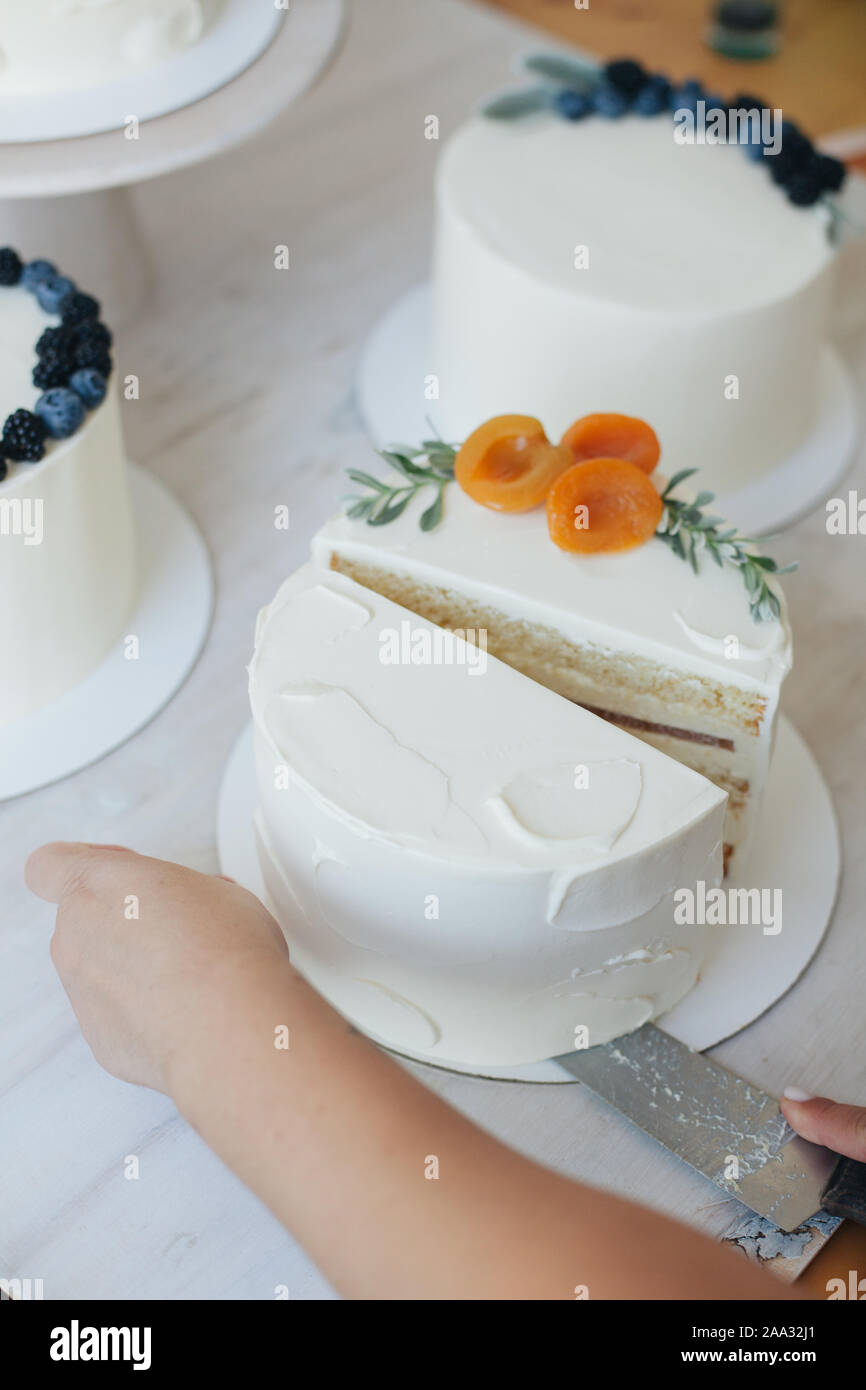 La donna il taglio di una torta con crema di burro glassa e pesche Foto Stock
