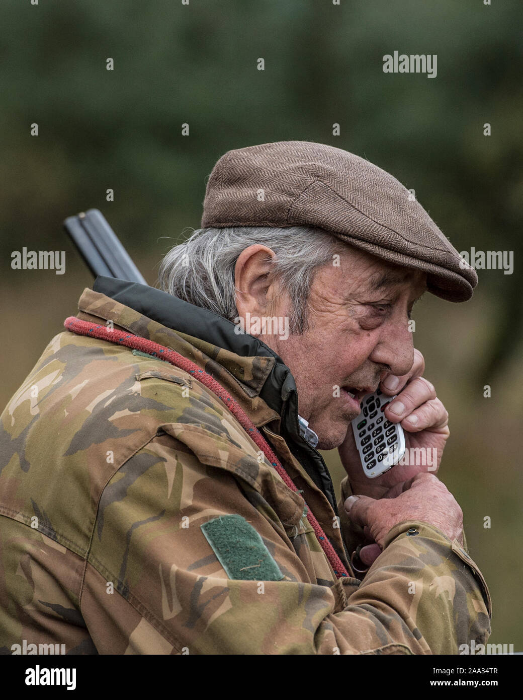 vecchio cacciatore anziano che usa il telefono cellulare Foto Stock