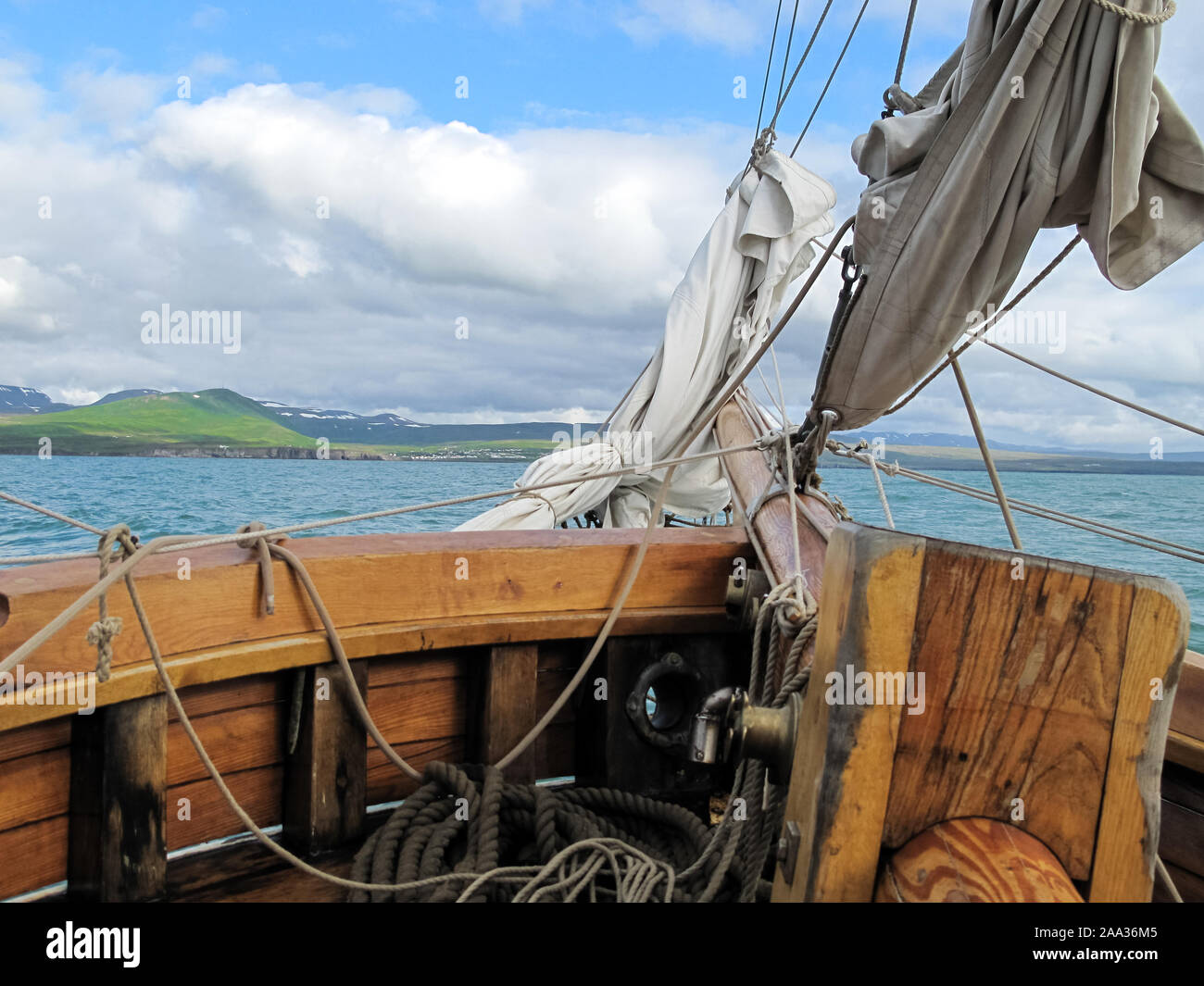 View from the bow of an old sailboat sailing in the Arctic sea with land in the background. Sailing concept Foto Stock