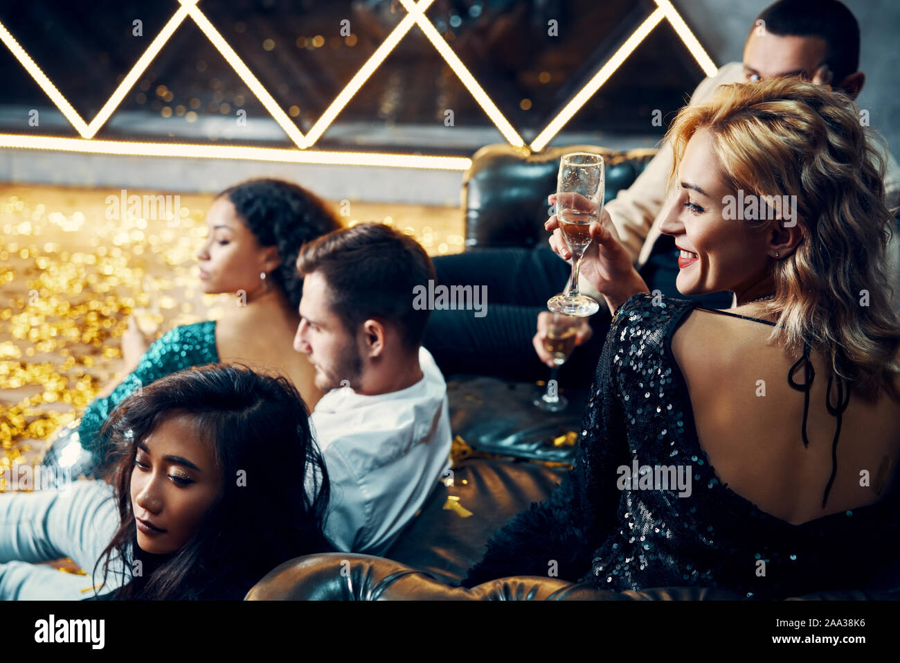 Diversi gruppi di giovani amici appendere fuori a bere un bicchiere di champagne al night club. Le persone godono di partito e divertirsi concept Foto Stock