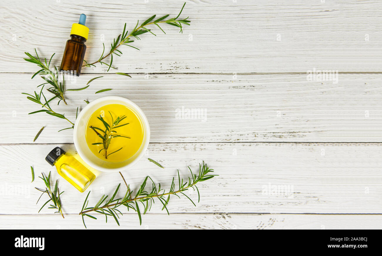 Essential oil bottle natural spa ingredients rosemary oil for aromatherapy and rosemary leaf on wood background / Organic cosmetics with extracts of h Foto Stock