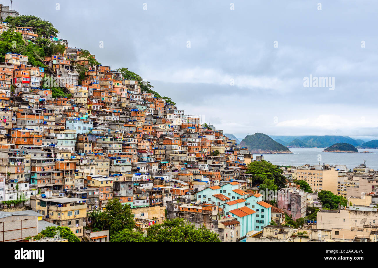 Favelas brasiliane sulla collina con centro città sotto al Tropical Bay, Rio de Janeiro, Brasile Foto Stock