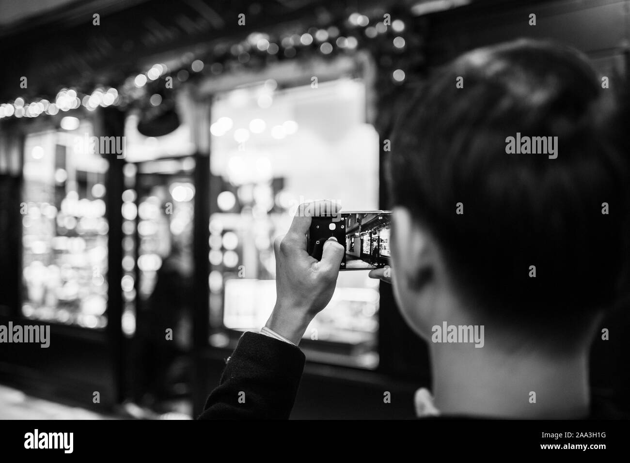 Strasburgo, Francia - Nov 23, 2017: vista posteriore di uomo adulto prendendo fotografie dell'illuminato e decorate vetrina ingresso della tradizionale francese Foto Stock