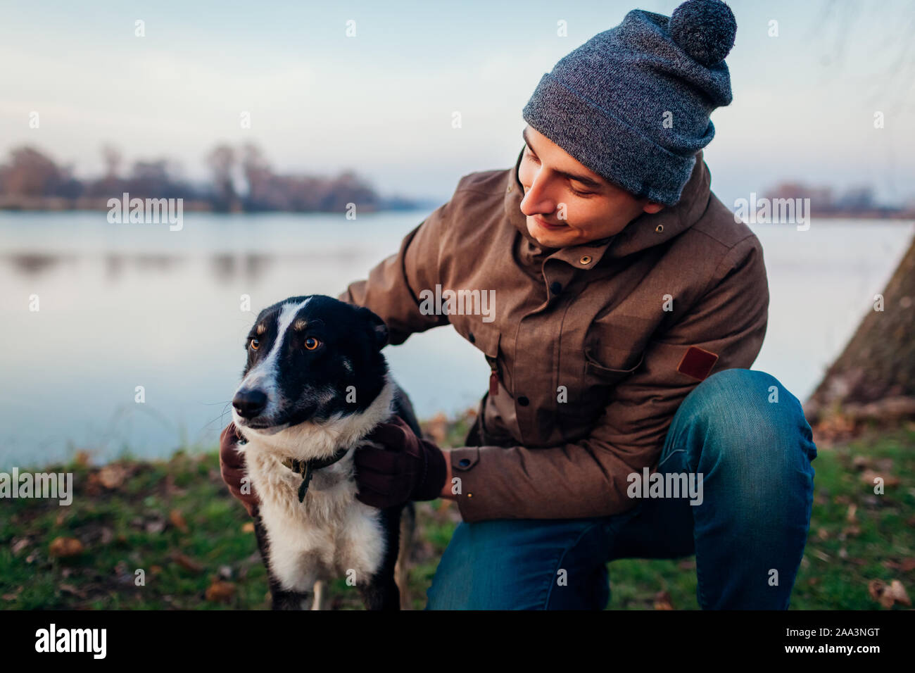 L'uomo gioca con il cane in autunno parco dal lago. Happy pet avente il divertimento all'aperto Foto Stock