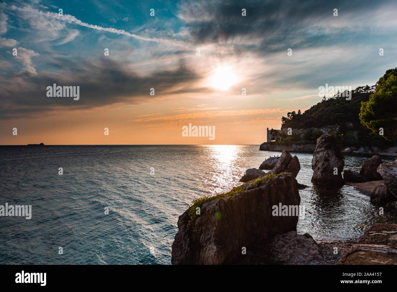 Vista spettacolare della costa del Mare Mediterraneo a Trieste in Italia mentre il tramonto, con il castello di Miramare (Castello di Miramare) in background. Foto Stock