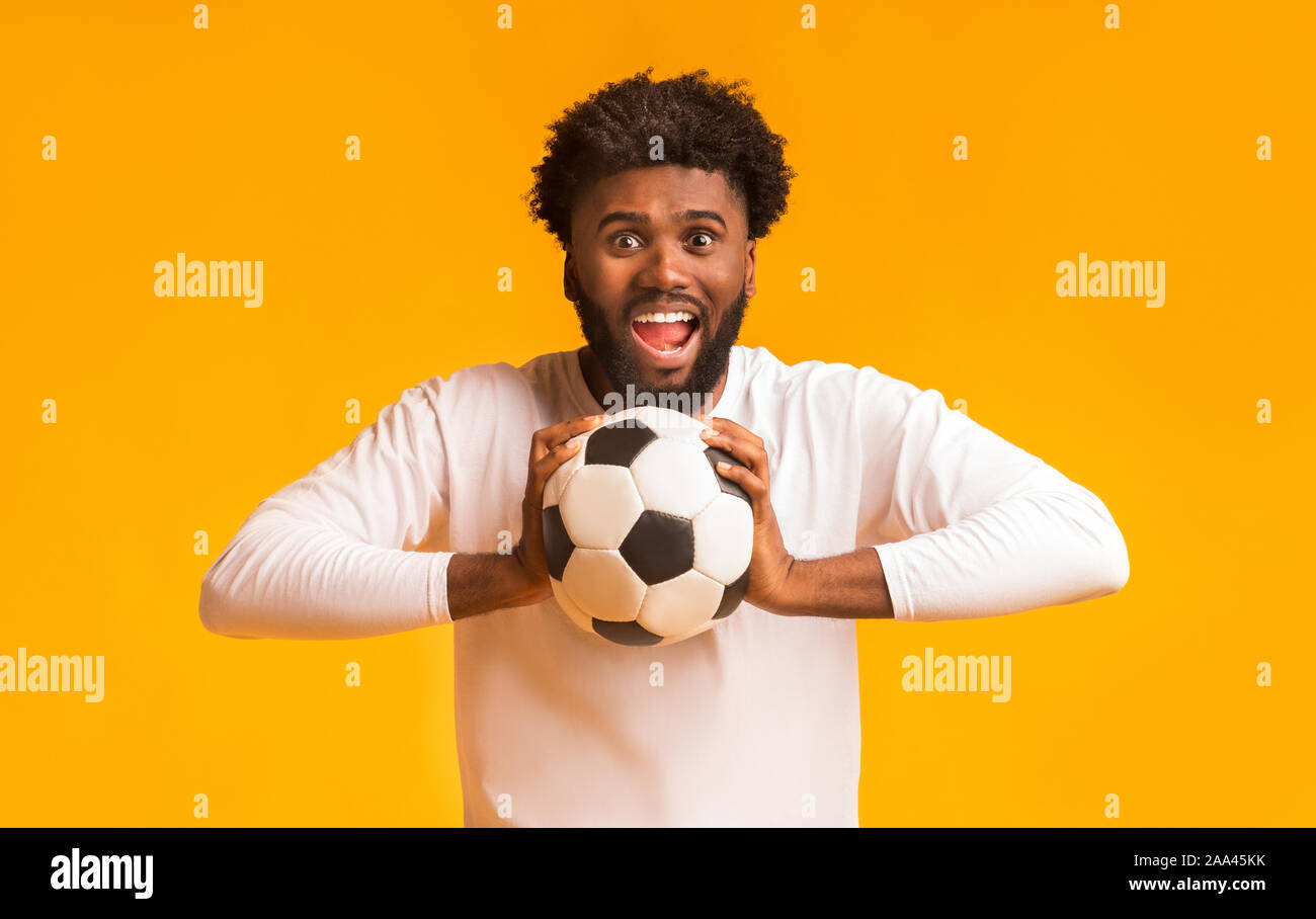 Appassionato di calcio con sfera piena di emozioni su sfondo arancione Foto Stock