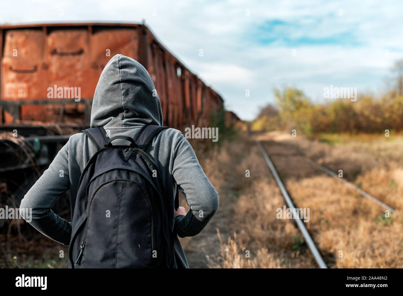 Donna senzatetto con zaino allontanarsi da tutto e da tutti, vista posteriore delle donne in cammino tra abbandonato i vagoni del treno e ferrovia obsoleti via Foto Stock