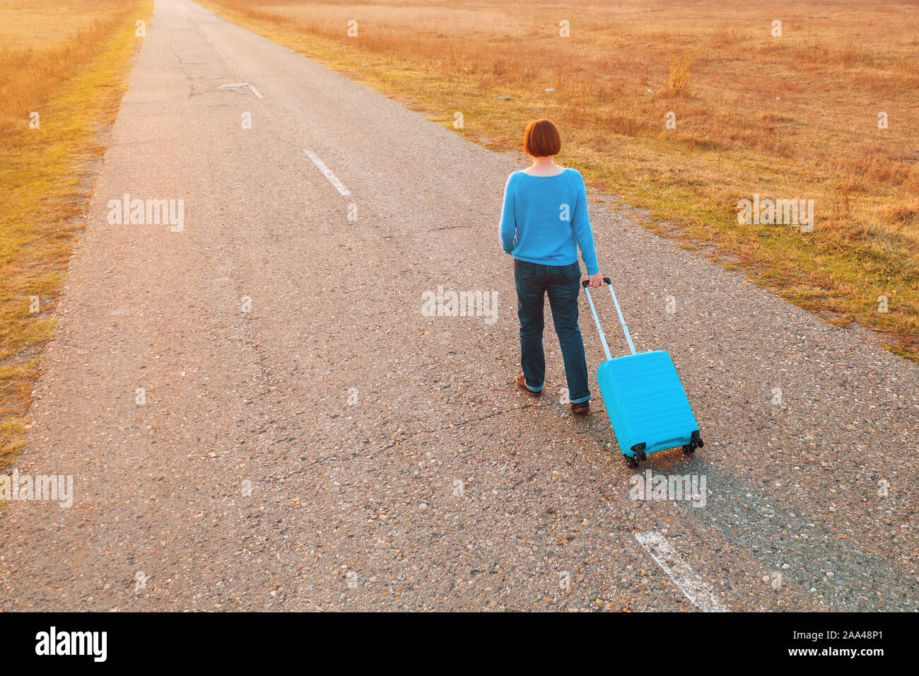 Tirando la donna valigia viaggio bagagli su strada in autunno tramonto, elevato angolo vista da fuco pov Foto Stock