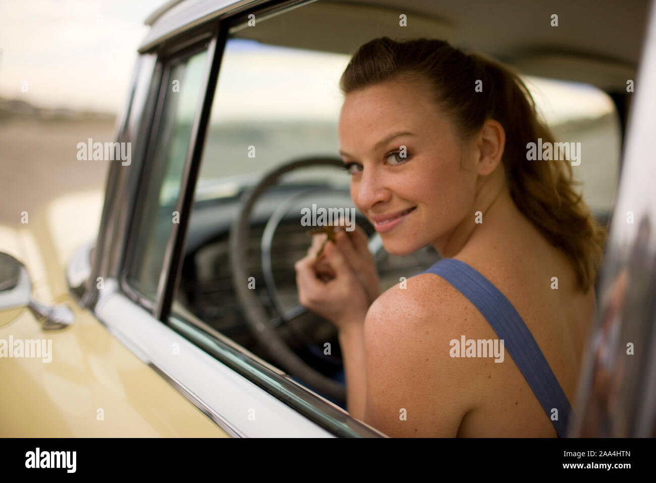 Donna seduta in auto retrò sorridente Foto Stock