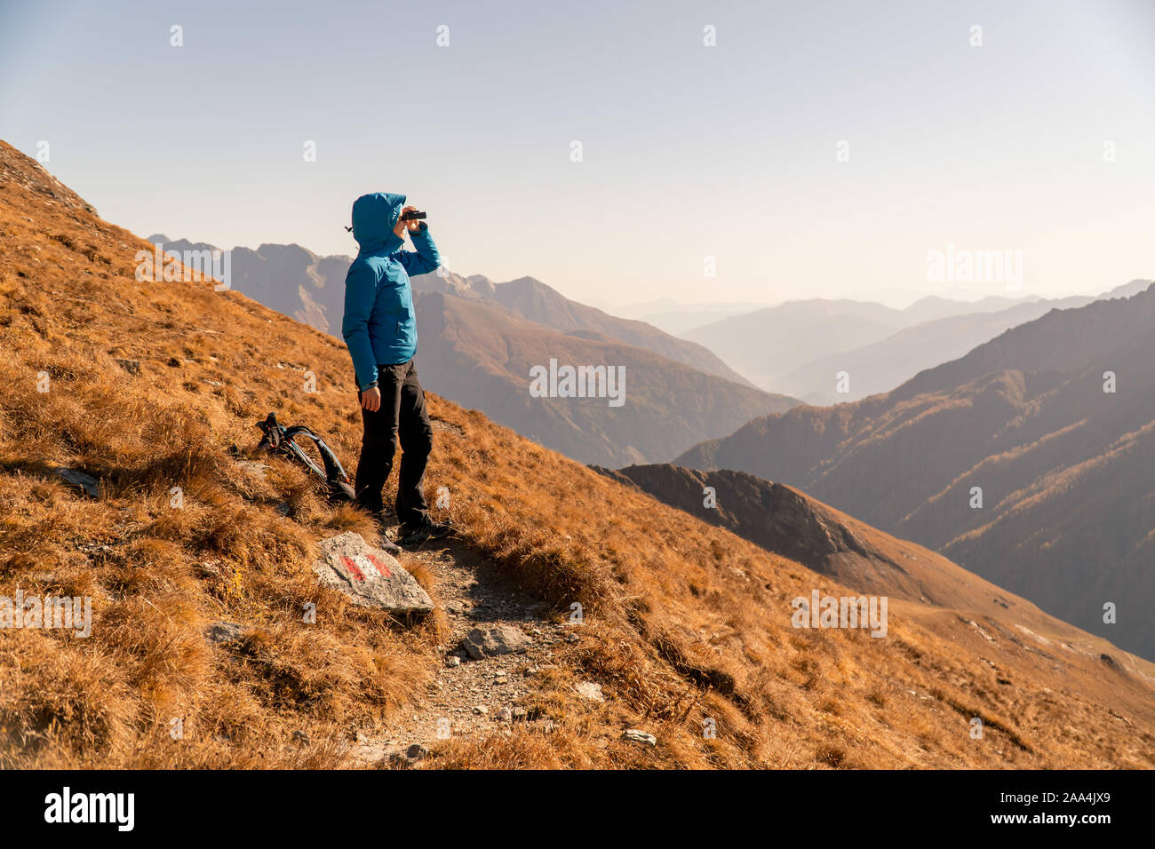 Escursionista in piedi in montagna cercando attraverso il binocolo, Bad Gastein, Salisburgo, Austria Foto Stock