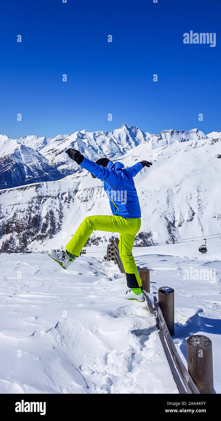 Uomo in un vestito di sci un salto nella neve fresca. L uomo è indossare giacca blu e neon verde pantaloni. Un sacco di polvere fresca neve intorno a lui. Alta mou Foto Stock