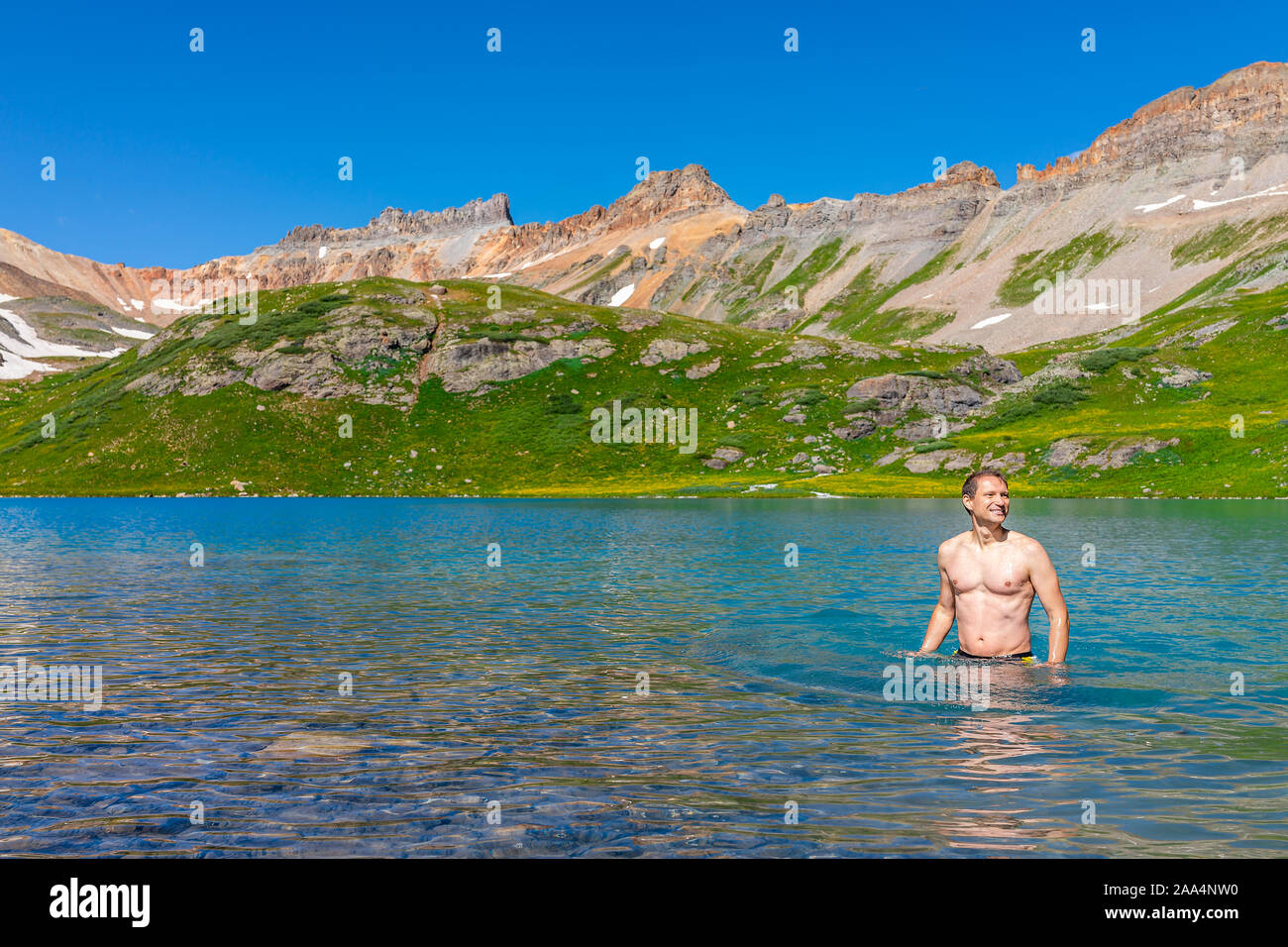 Giovani felici montare man standing nuotare nel freddo acqua colorata del Lago di ghiaccio sul famoso sentiero in Silverton, Colorado in San Juan Mountains in estate Foto Stock