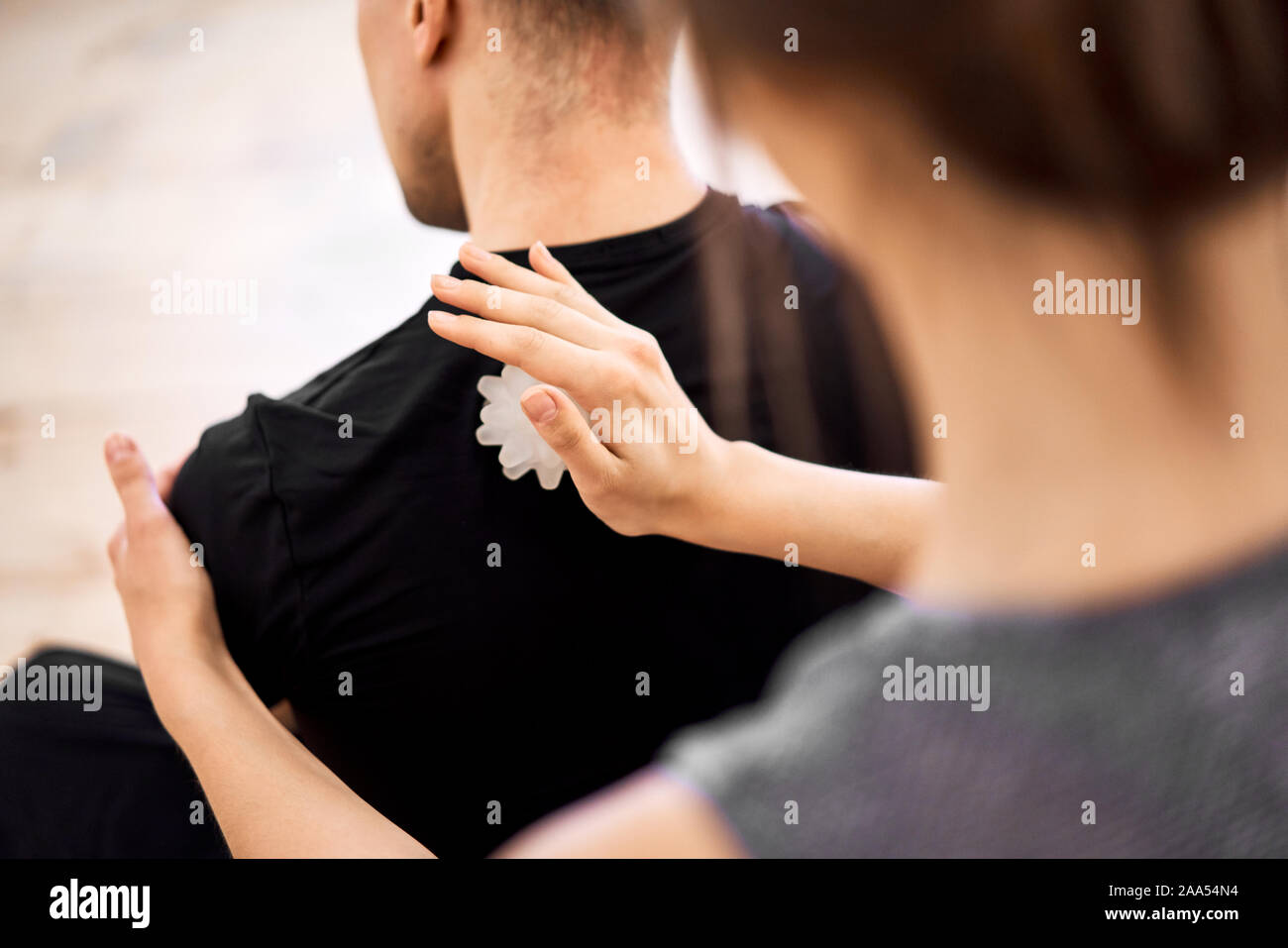 Donna facendo massaggio alla schiena per uomo con sfera di massaggio in camera, vicino fino Foto Stock