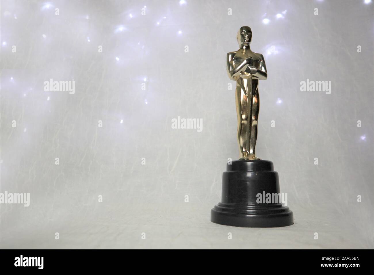 La statua dorata di Oscar su uno sfondo bianco, con illuminazione intorno a un prestigioso figura. Il successo e il concetto di vittoria Foto Stock