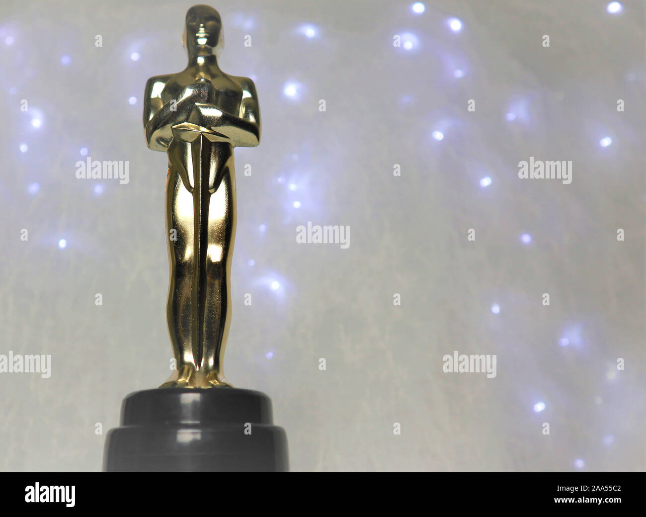 La statua dorata di Oscar su uno sfondo bianco, con illuminazione intorno a un prestigioso figura. Il successo e la vittoria del concetto. Foto Stock