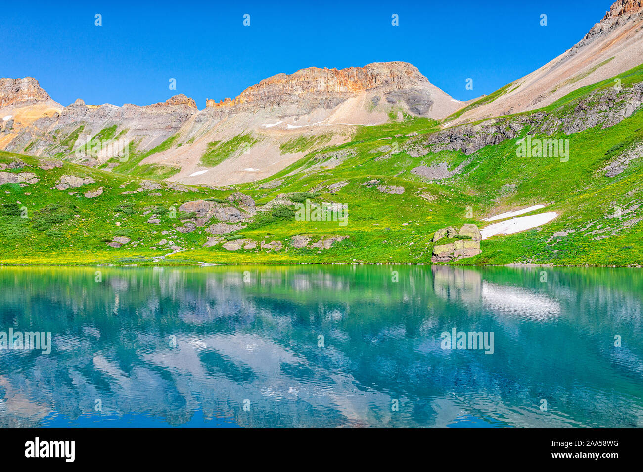 Vista del paesaggio di erba verde prato e ghiaccio acqua di lago vicino a riflessione Silverton, Colorado in agosto 2019 estate sul vertice con la neve Foto Stock