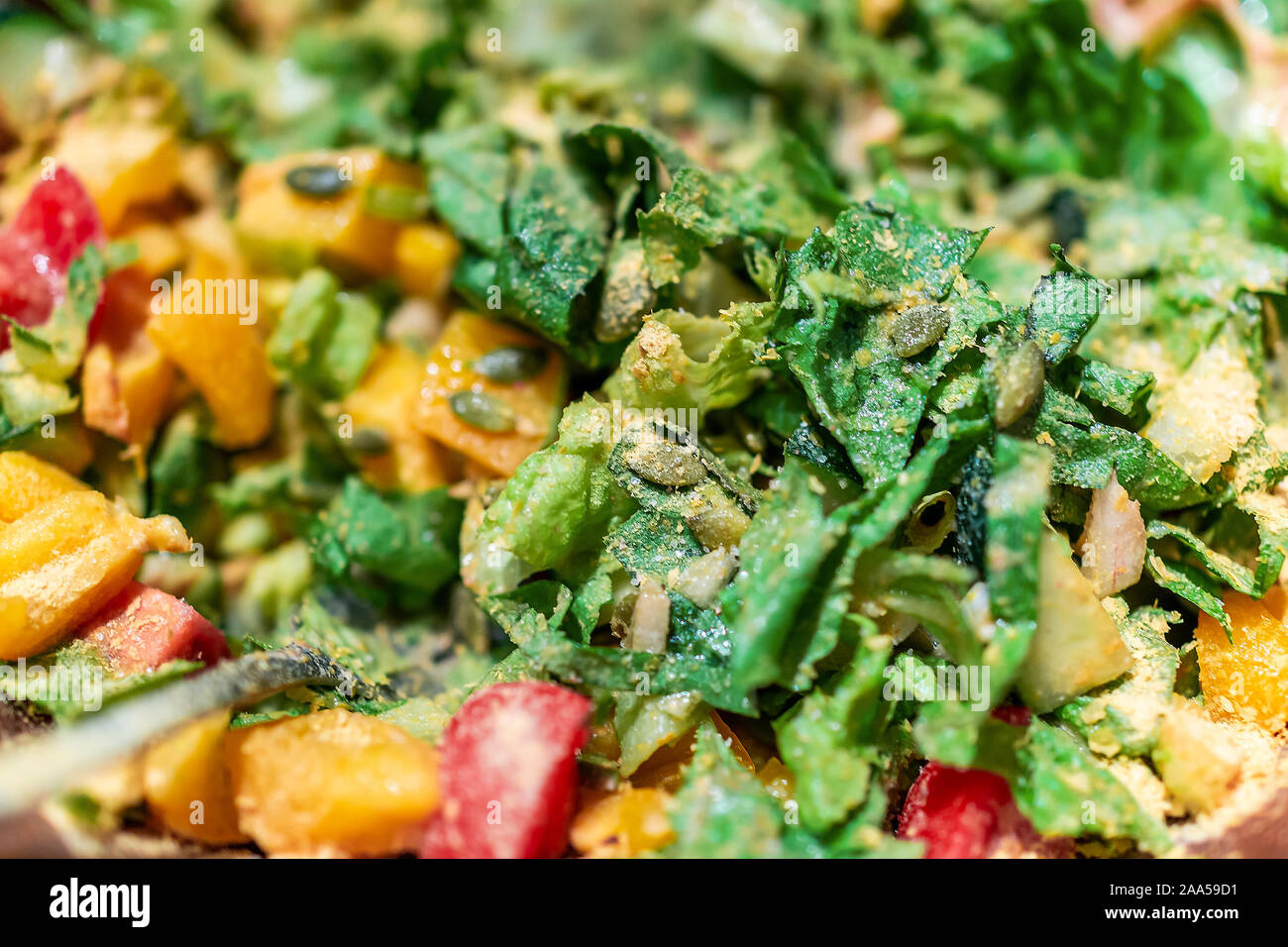 Un trito di verdure verdi insalata closeup macro con fresco vegane lattuga romana e pomodori rossi, giallo peperoni, nutrizionali e di lievito con pumpki Foto Stock