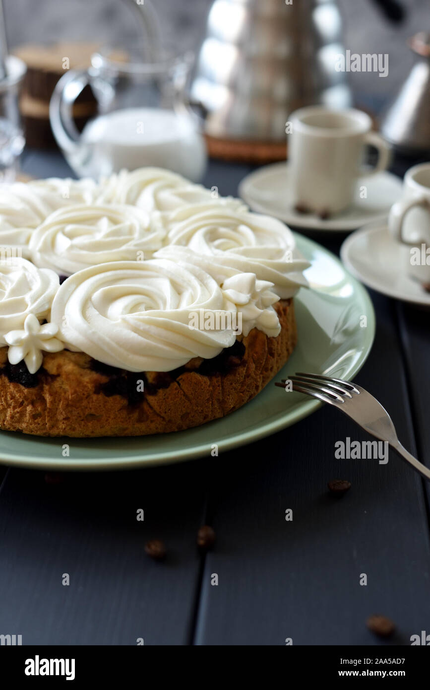 Close up di torte fatte in casa con crema di cocco volute servita con caffè su sfondo scuro copia spazio. Ancora in vita con illuminazione naturale con copyspace Foto Stock