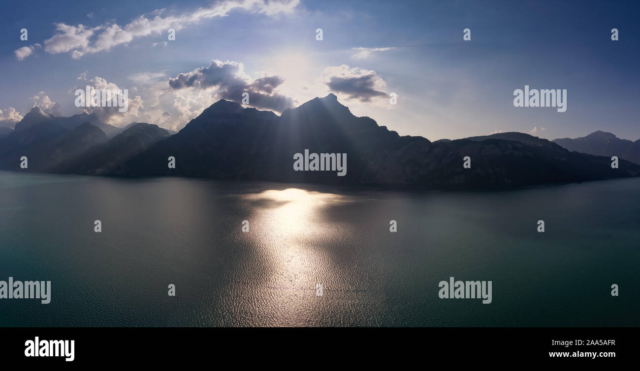 Lago Grande panorama delle Alpi svizzere sul pomeriggio soleggiato. Verde acqua sul ghiacciaio riflettono la linea di montagna e le poche nuvole Foto Stock