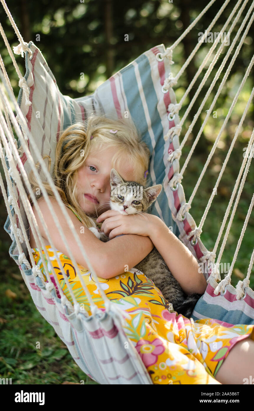 Bella ragazza in amaca avente una buona volta con cute cat in bella e soleggiata giornata estiva Foto Stock