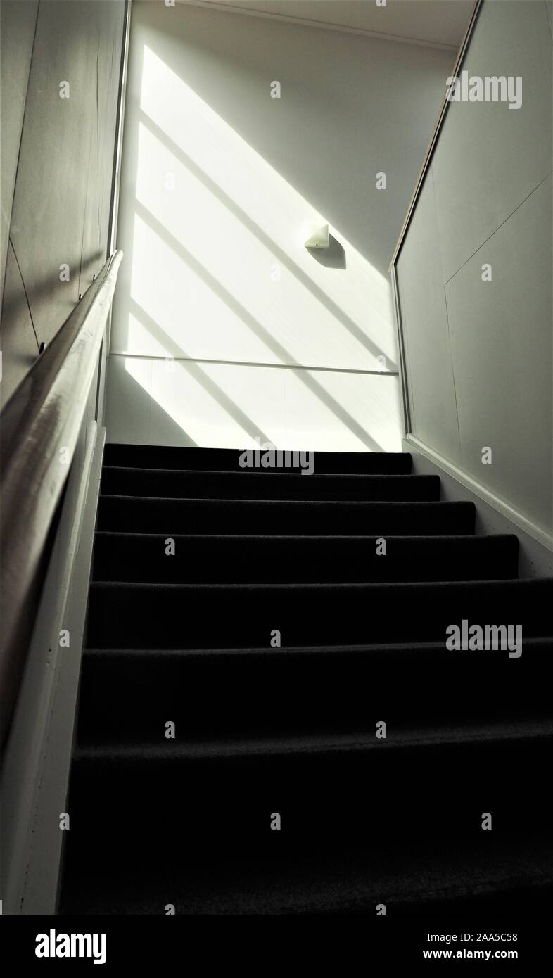 Una scalinata illuminate dal sole in un vecchio edificio per uffici Foto Stock