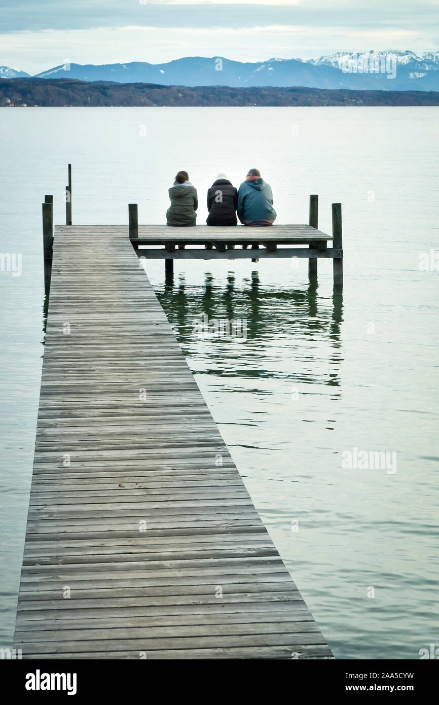 Drei Menschen auf einem Steg am Starnberger See, Deutschland im inverno Foto Stock